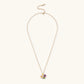Gold-plated necklace with pink and purple enamel flower pendant featuring crystal accents on cream background